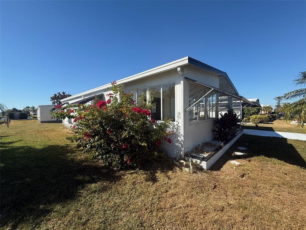 A white mobile home features a large bougainvillea bush and an attached sunroom — 731 BLANCA, NORTH PORT, FL