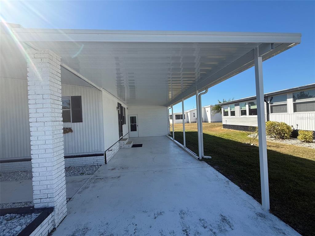 A white carport with a metal roof extends from the side of a mobile home — 731 BLANCA, NORTH PORT, FL