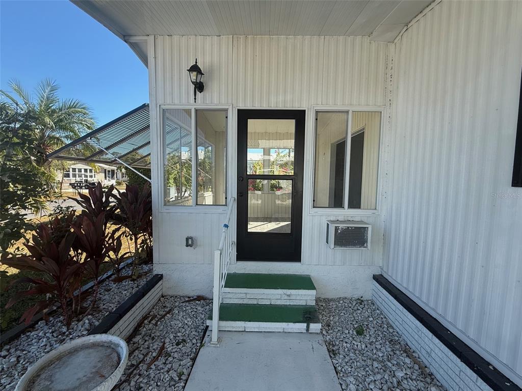 The exterior of a mobile home features a white front door, steps, and windows — 731 BLANCA, NORTH PORT, FL
