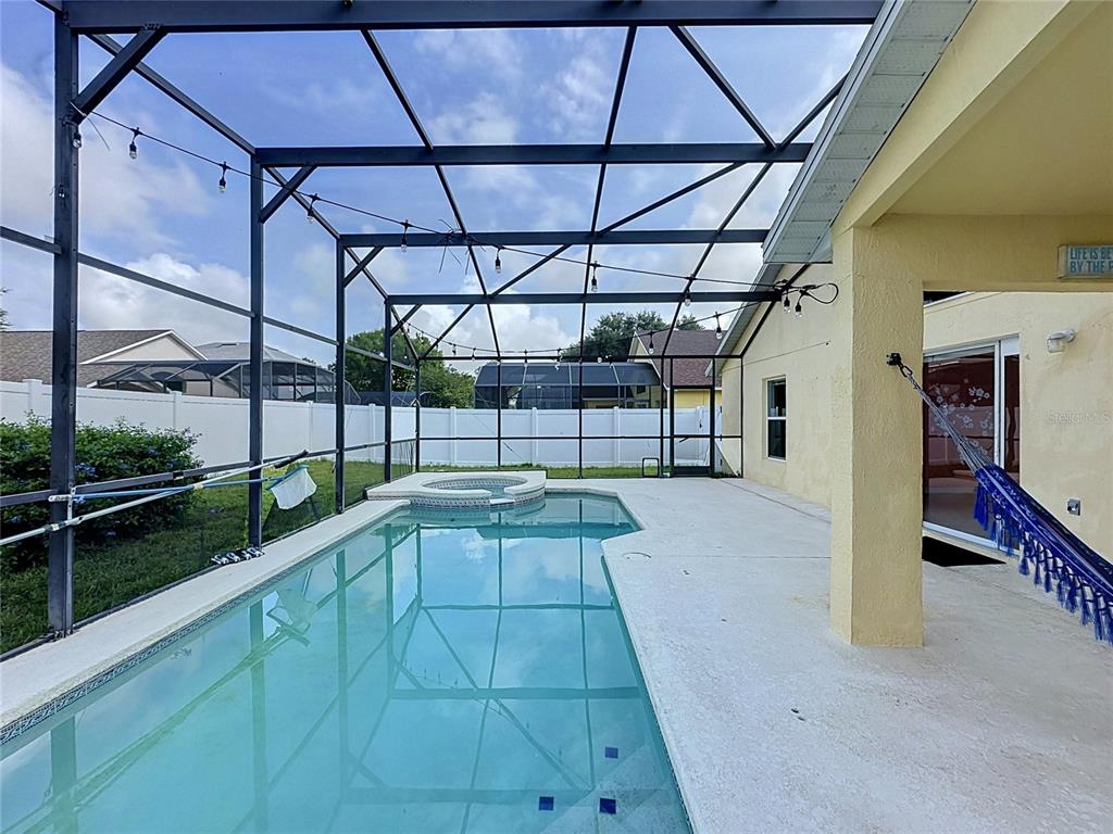A screened-in patio features a swimming pool, a small spa, and a light-colored concrete deck — 3122 MONTSERRAT WAY, HAINES CITY, FL