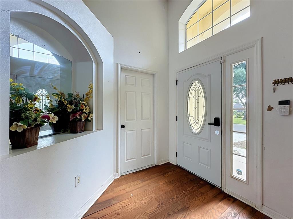 An entryway features wood flooring, a white front door with a sidelight, and an arched niche — 3122 MONTSERRAT WAY, HAINES CITY, FL