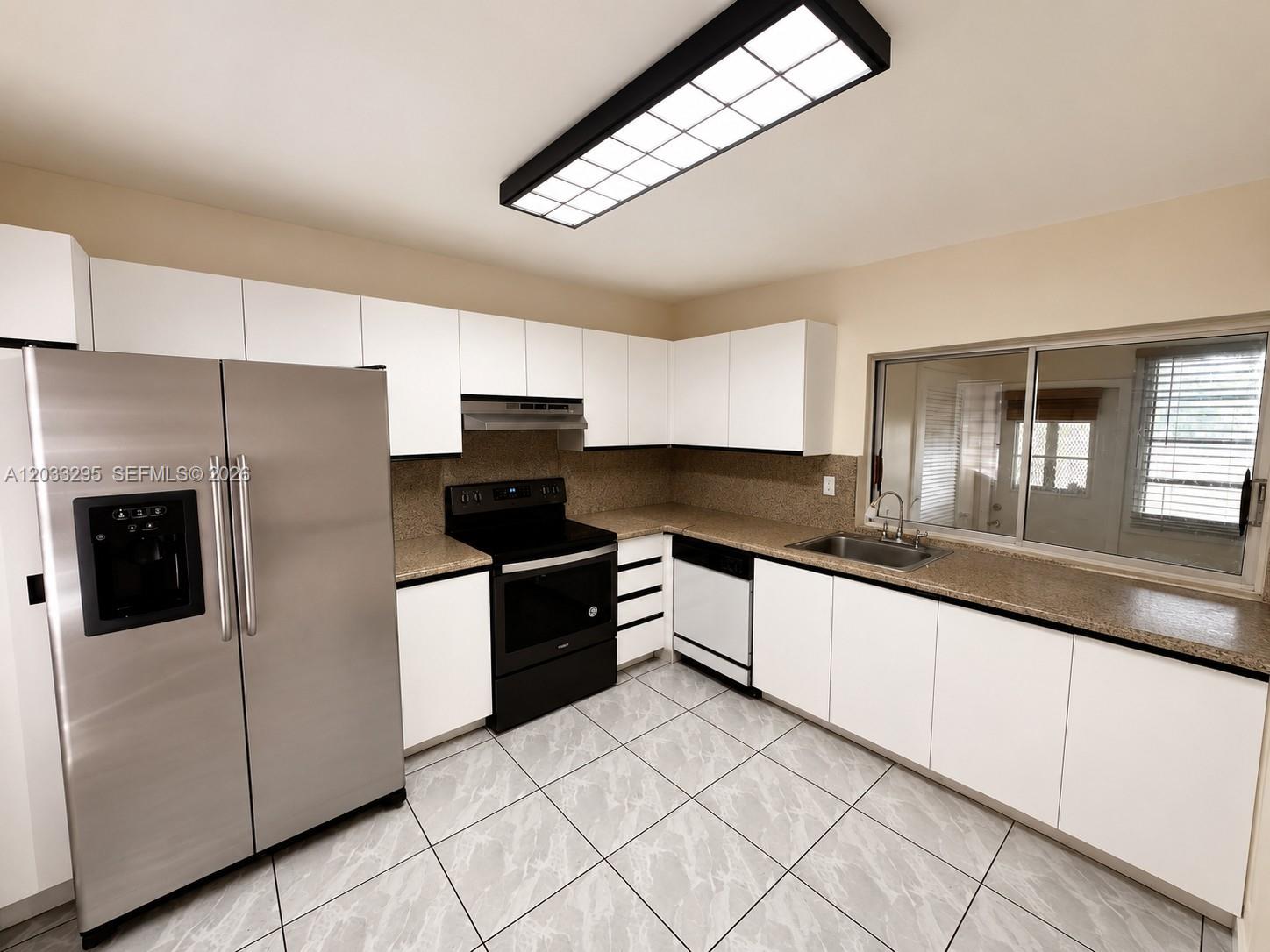 A kitchen features white cabinets, stainless steel appliances, speckled countertops, and light-colored tiled floors — 17215 SW 112 CT, Miami FL 33157, MIAMI, FL