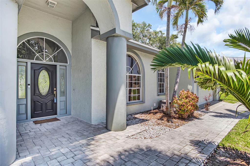 The front entrance features a dark door with a glass insert, arched windows, and pavers — 2654 CRYSTAL CIRCLE, DUNEDIN, FL