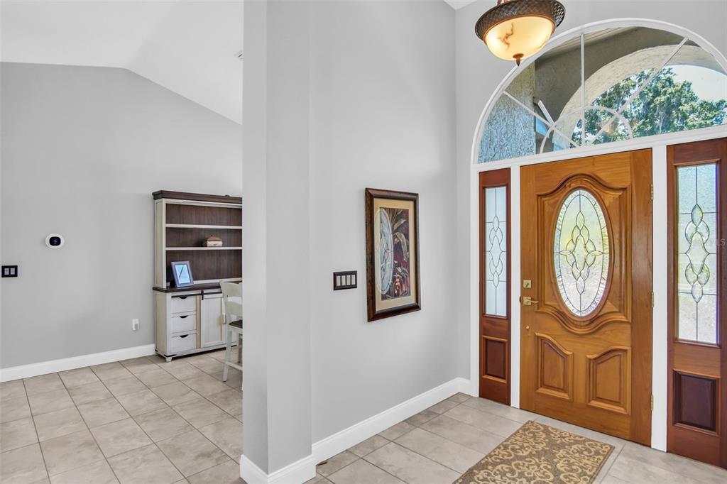 A bright entryway features a wooden front door with glass inserts and tiled flooring — 2654 CRYSTAL CIRCLE, DUNEDIN, FL