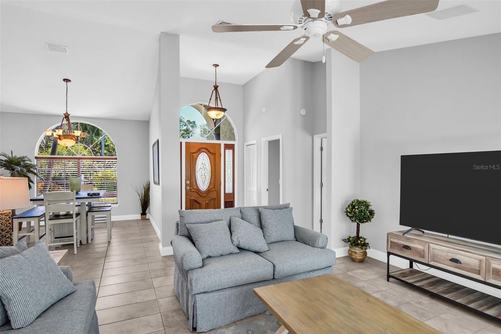A living room features a gray sofa, a television, and an adjacent dining area — 2654 CRYSTAL CIRCLE, DUNEDIN, FL