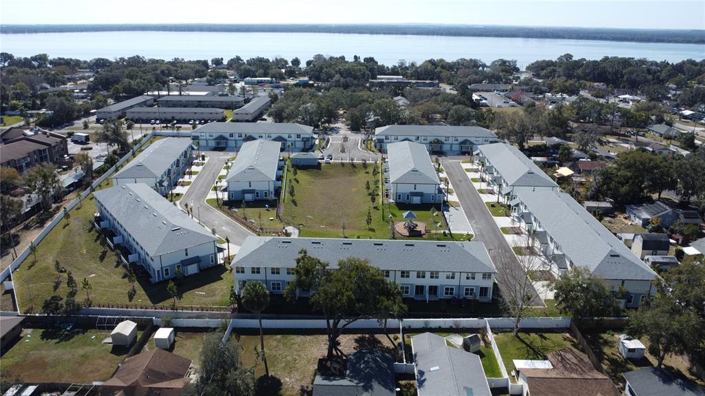 An aerial view shows a residential complex with multiple townhome buildings surrounding a central courtyard — 1129 E CAROLINE STREET, TAVARES, FL