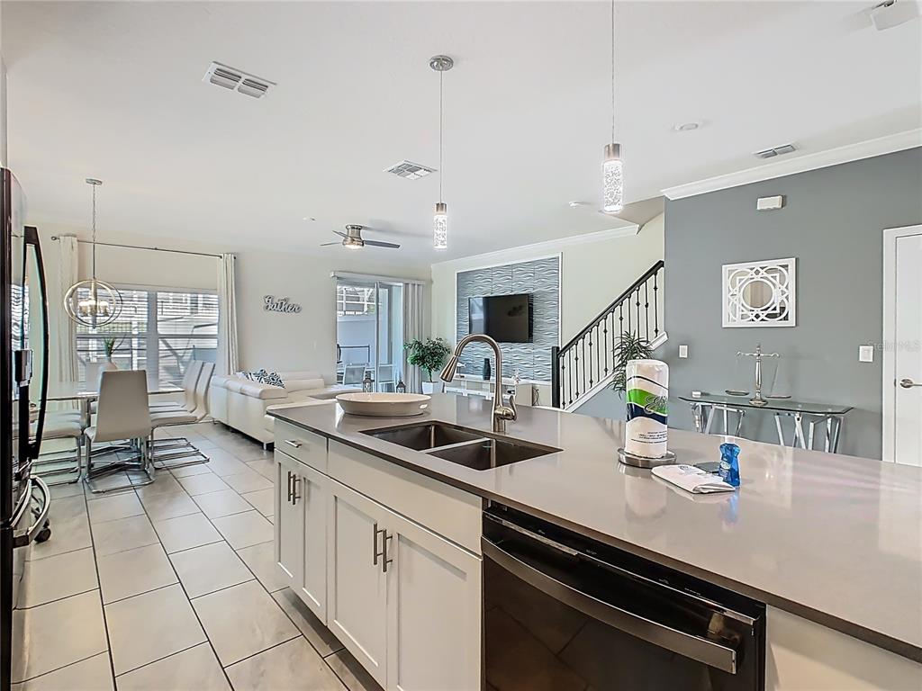 A modern kitchen island with a double sink overlooks an open-concept living and dining area — 1264 CHALLENGE DRIVE UNIT 1264, DAVENPORT, FL