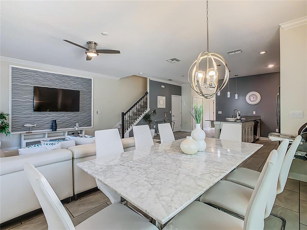A dining area with a marble table and white chairs sits before a living room — 1264 CHALLENGE DRIVE UNIT 1264, DAVENPORT, FL