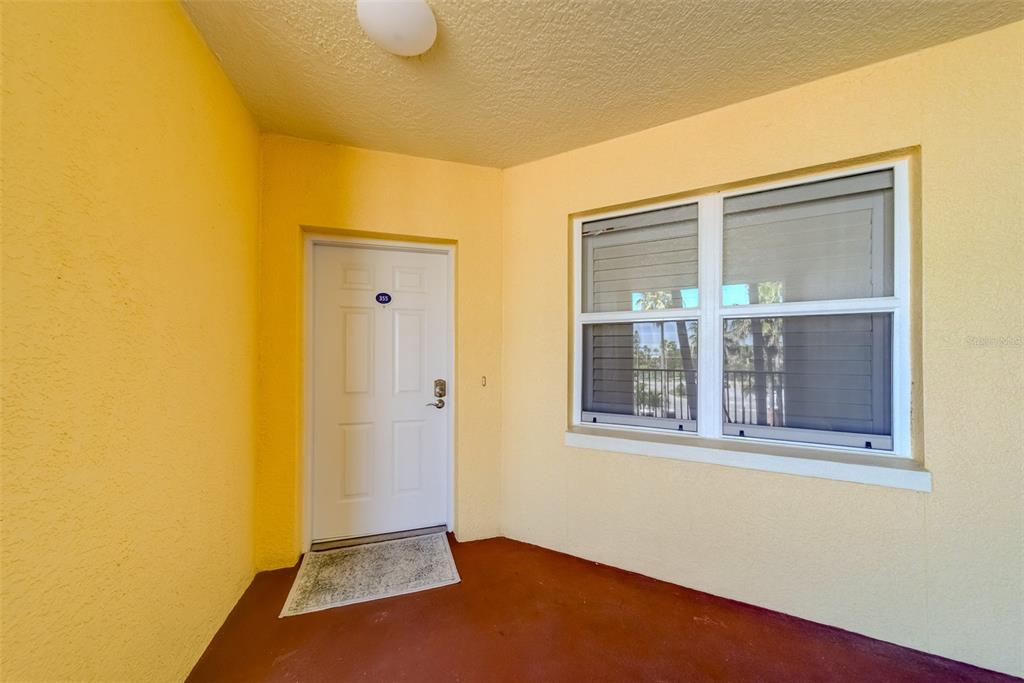 A yellow-walled entryway features a white door with a number and a large window — 16500 GULF BOULEVARD UNIT 355, NORTH REDINGTON BEACH, FL
