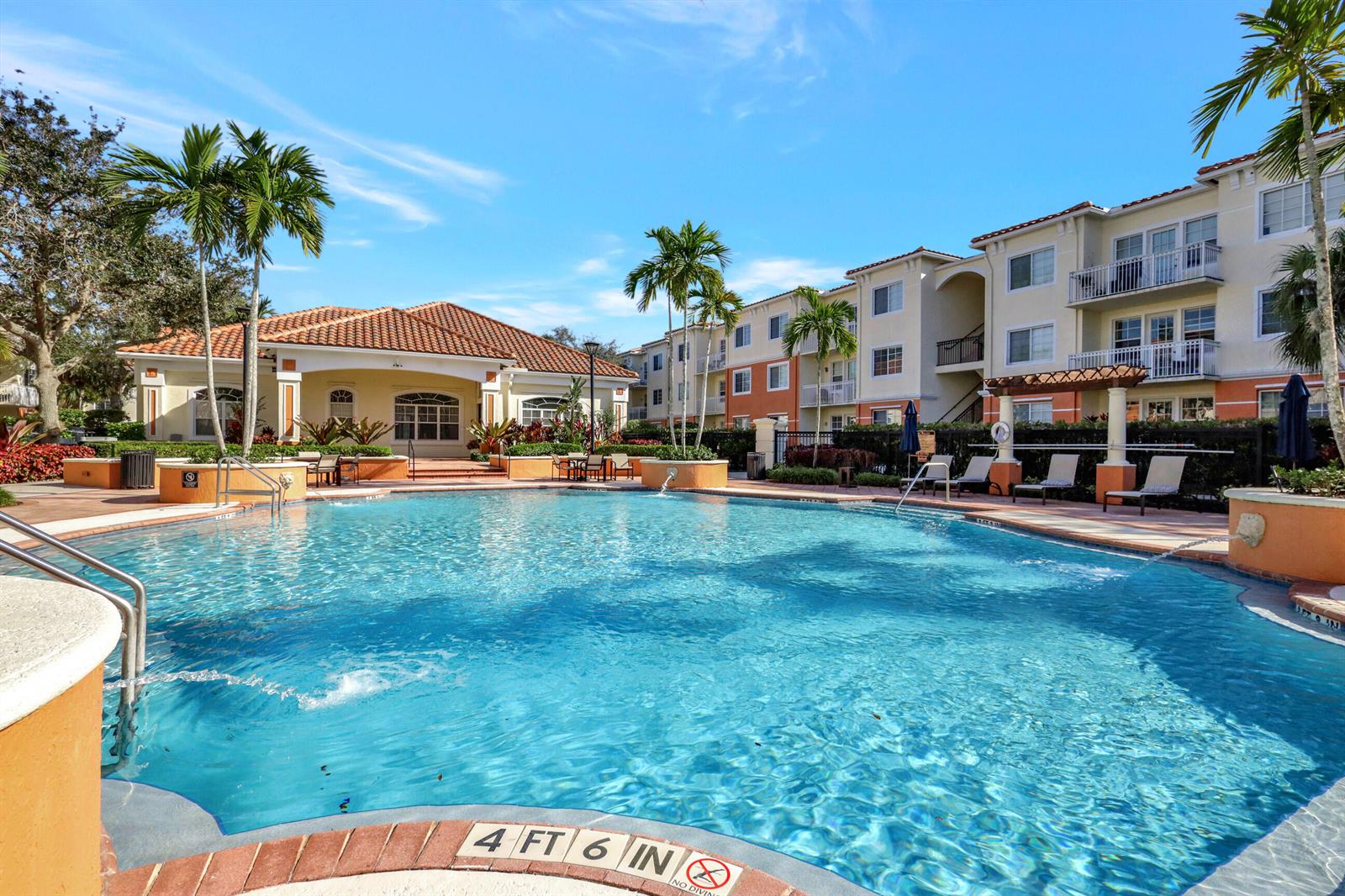 A swimming pool with a depth marker sits in front of a multi-story apartment building — 9873 Baywinds Drive # 5302, West Palm Beach FL 33411, WEST PALM BEACH, FL