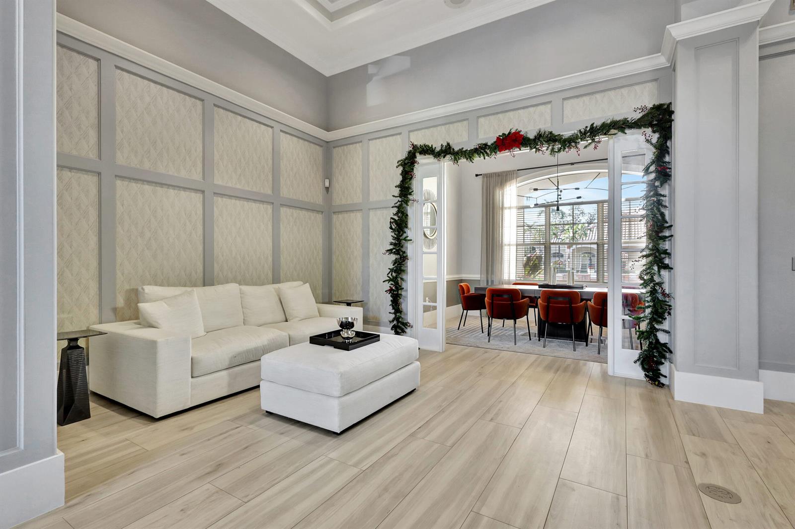 A living room with a white sofa and ottoman opens into a dining room with orange chairs — 9873 Baywinds Drive # 5302, West Palm Beach FL 33411, WEST PALM BEACH, FL