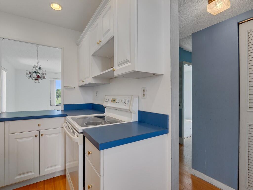 A kitchen features white cabinets, blue countertops, and a white electric range — 5373 SE Miles Grant Road # 208, Stuart FL 34997, STUART, FL