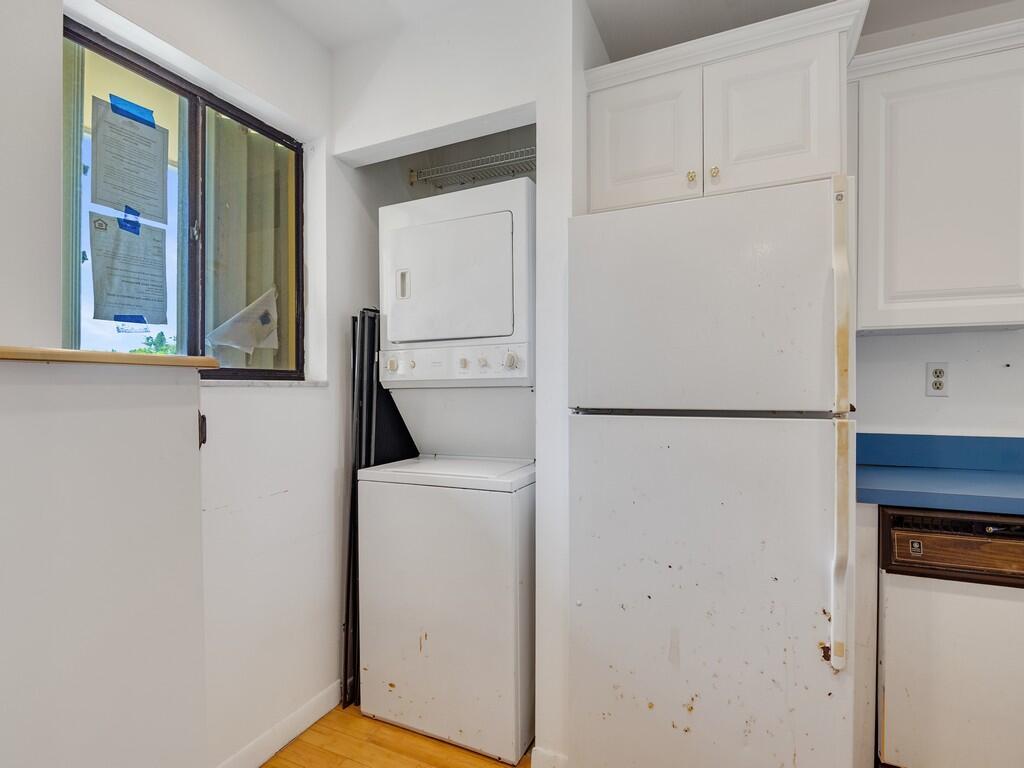 A kitchen area features a stacked washer and dryer unit next to a white refrigerator — 5373 SE Miles Grant Road # 208, Stuart FL 34997, STUART, FL