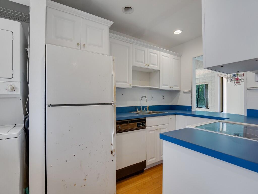 A kitchen features white cabinets, blue countertops, a white refrigerator, and a stackable laundry unit — 5373 SE Miles Grant Road # 208, Stuart FL 34997, STUART, FL