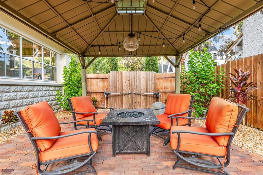 A patio features a metal gazebo over a fire pit surrounded by four orange chairs — 44 SE 9TH TERRACE, OCALA, FL