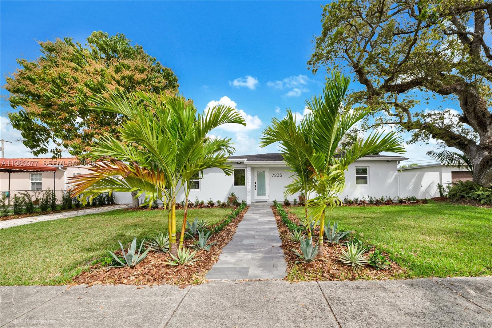 A single-story white house features a stone walkway flanked by palm trees and landscaping — 7235 SW 39th St, Miami FL 33155, MIAMI, FL