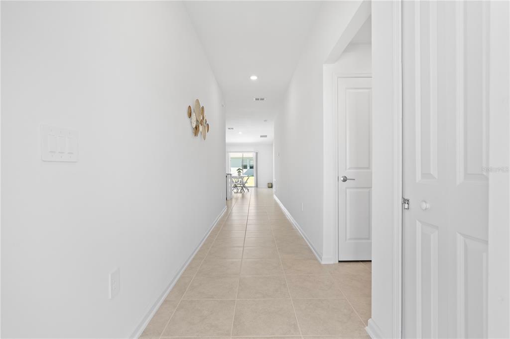 A long, tiled hallway with white walls leads toward a bright living area — 1011 JOHN JACOB ROAD, DAVENPORT, FL