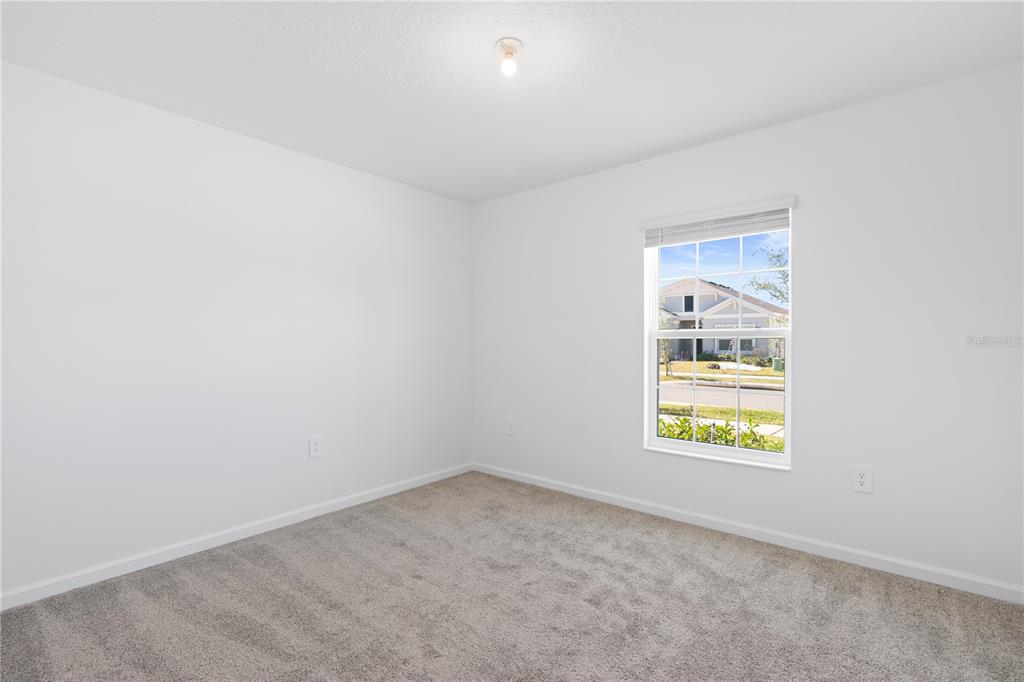 An empty bedroom features white walls, gray carpeting, a single window, and a ceiling light — 1011 JOHN JACOB ROAD, DAVENPORT, FL