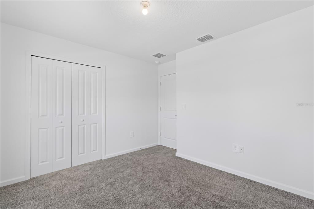 A bedroom with white walls, gray carpet, a closet with bifold doors, and a doorway — 1011 JOHN JACOB ROAD, DAVENPORT, FL