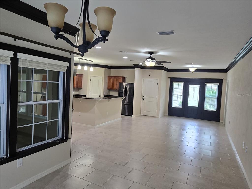 An open-concept kitchen and living area features tile flooring, dark trim, and a chandelier — 19176 NW 228TH STREET, HIGH SPRINGS, FL