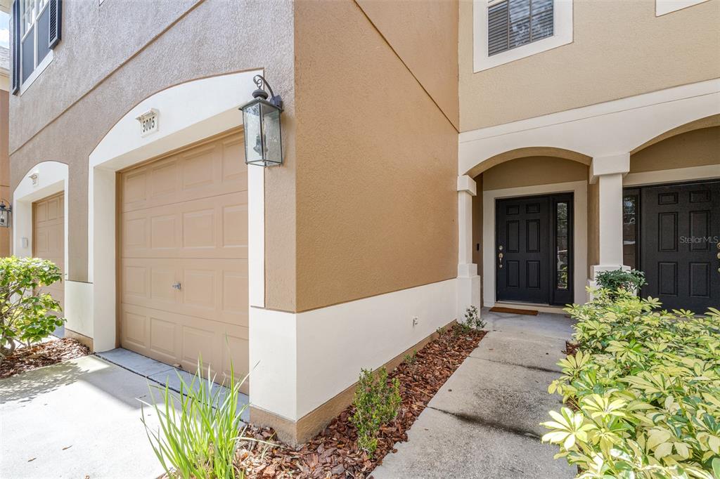 A tan townhouse exterior features a garage, a black front door, and a concrete walkway — 5005 BARNSTEAD DRIVE, RIVERVIEW, FL