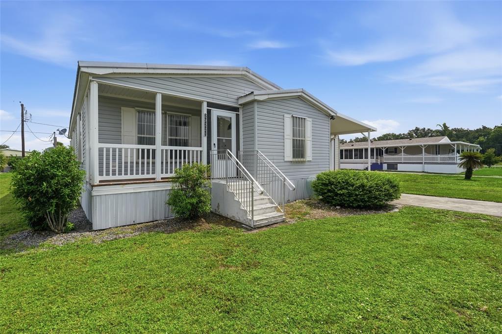 A light gray manufactured home with a screened front porch and concrete steps — 29228 MARYLU AVENUE, PUNTA GORDA, FL