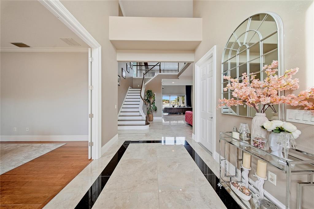 A foyer with marble flooring, a staircase, and a console table with a mirror — 10711 CORY LAKE DRIVE, TAMPA, FL
