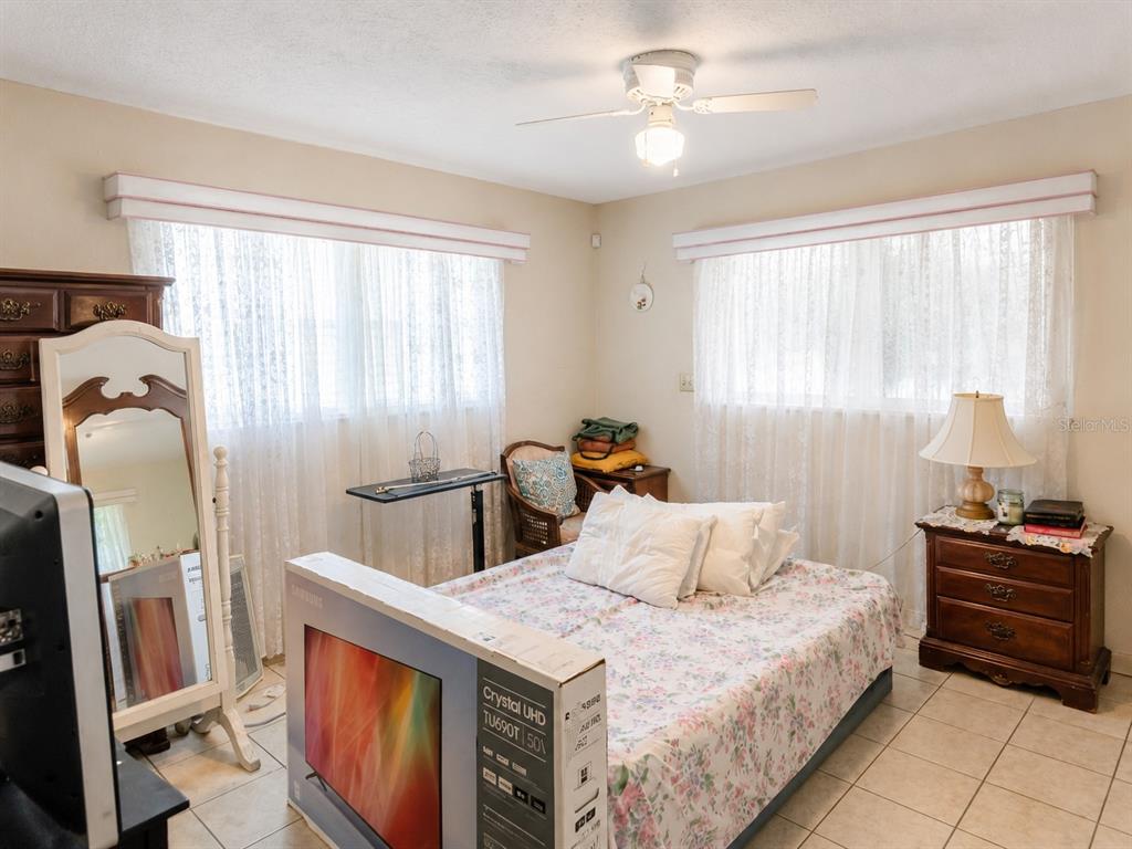 A bedroom features a bed with floral bedding, a ceiling fan, and two large windows — 6035 7TH STREET S, ST PETERSBURG, FL