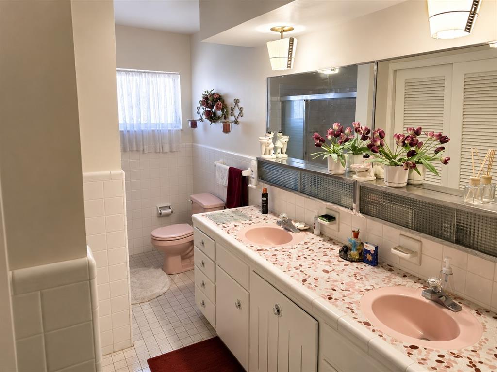 A bathroom features a double vanity with pink sinks, terrazzo countertops, and a pink toilet — 6035 7TH STREET S, ST PETERSBURG, FL
