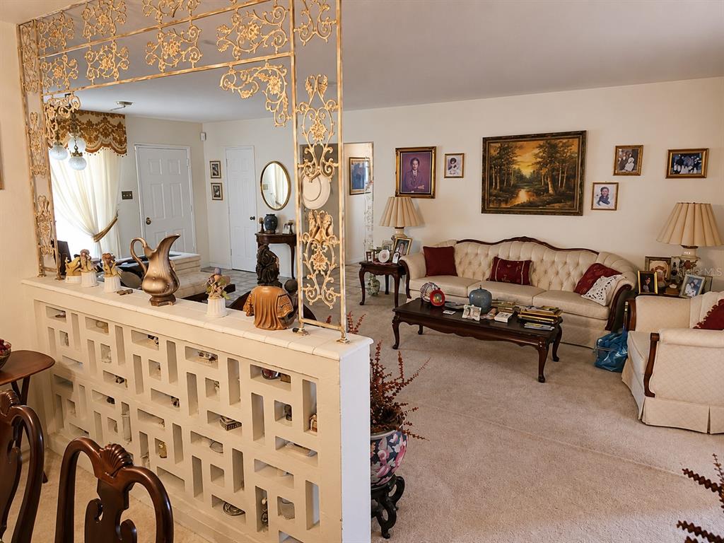 A living room features a decorative metal room divider, a white sofa, and wall art — 6035 7TH STREET S, ST PETERSBURG, FL