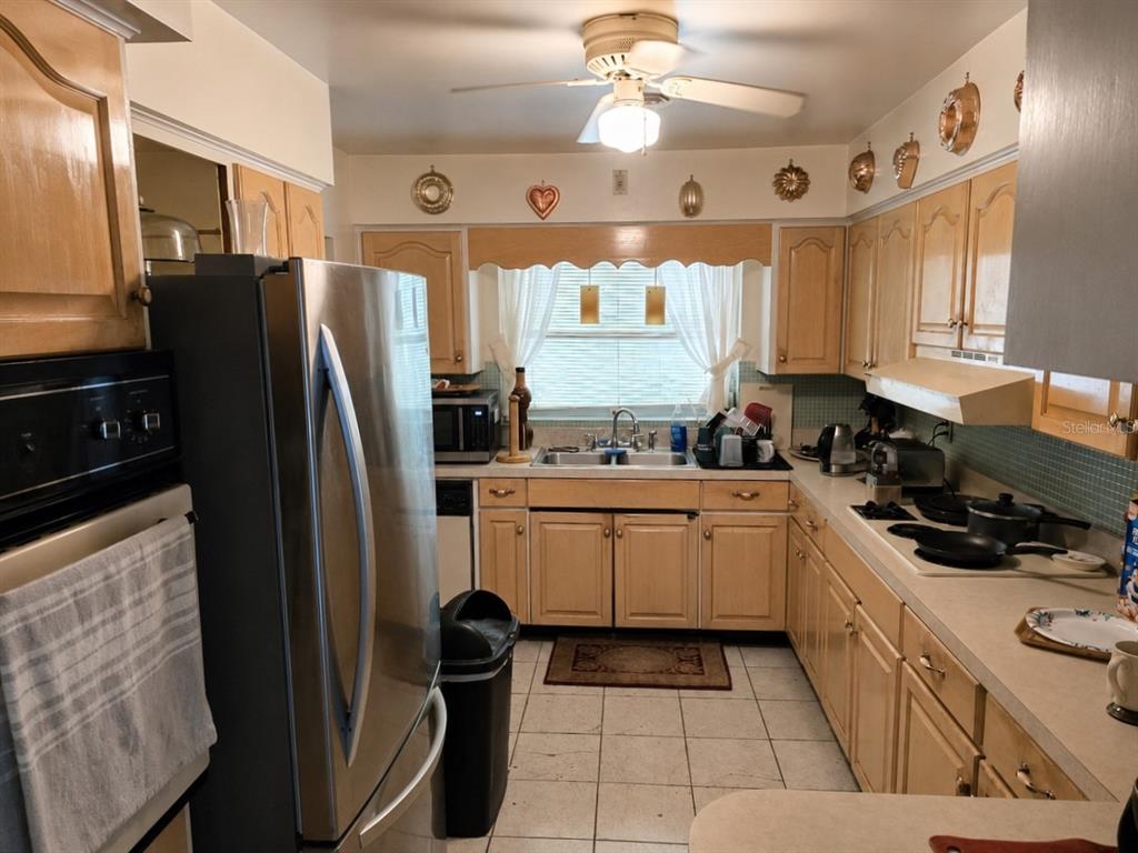 A kitchen features light wood cabinets, stainless steel appliances, a double sink, and tiled floors — 6035 7TH STREET S, ST PETERSBURG, FL