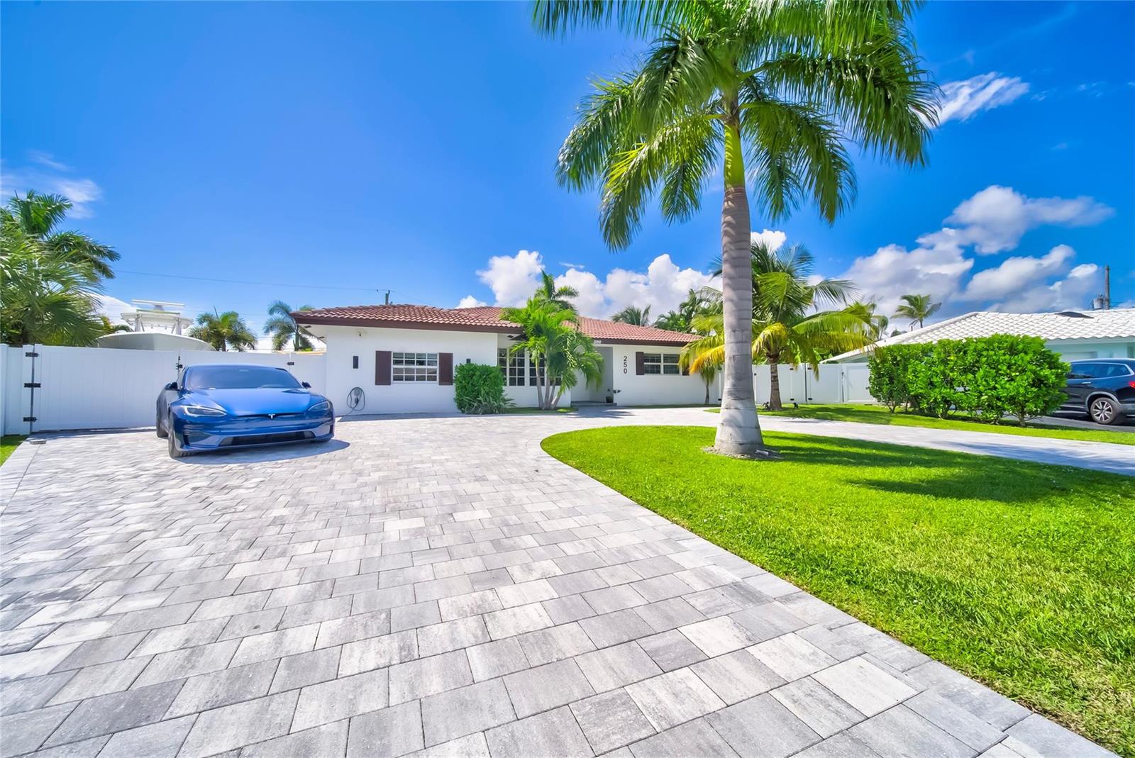 A single-story house with a paved driveway, a blue Tesla, and palm trees — 250 NE 27th Court, Boca Raton FL 33431, BOCA RATON, FL