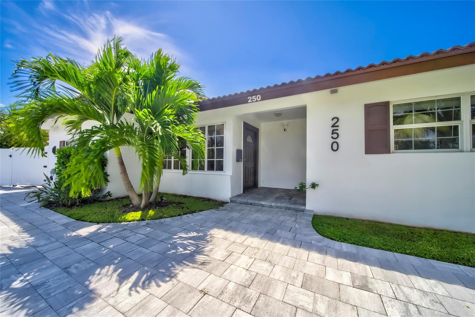 A white house exterior features a palm tree, a paved walkway, and a covered entryway — 250 NE 27th Court, Boca Raton FL 33431, BOCA RATON, FL