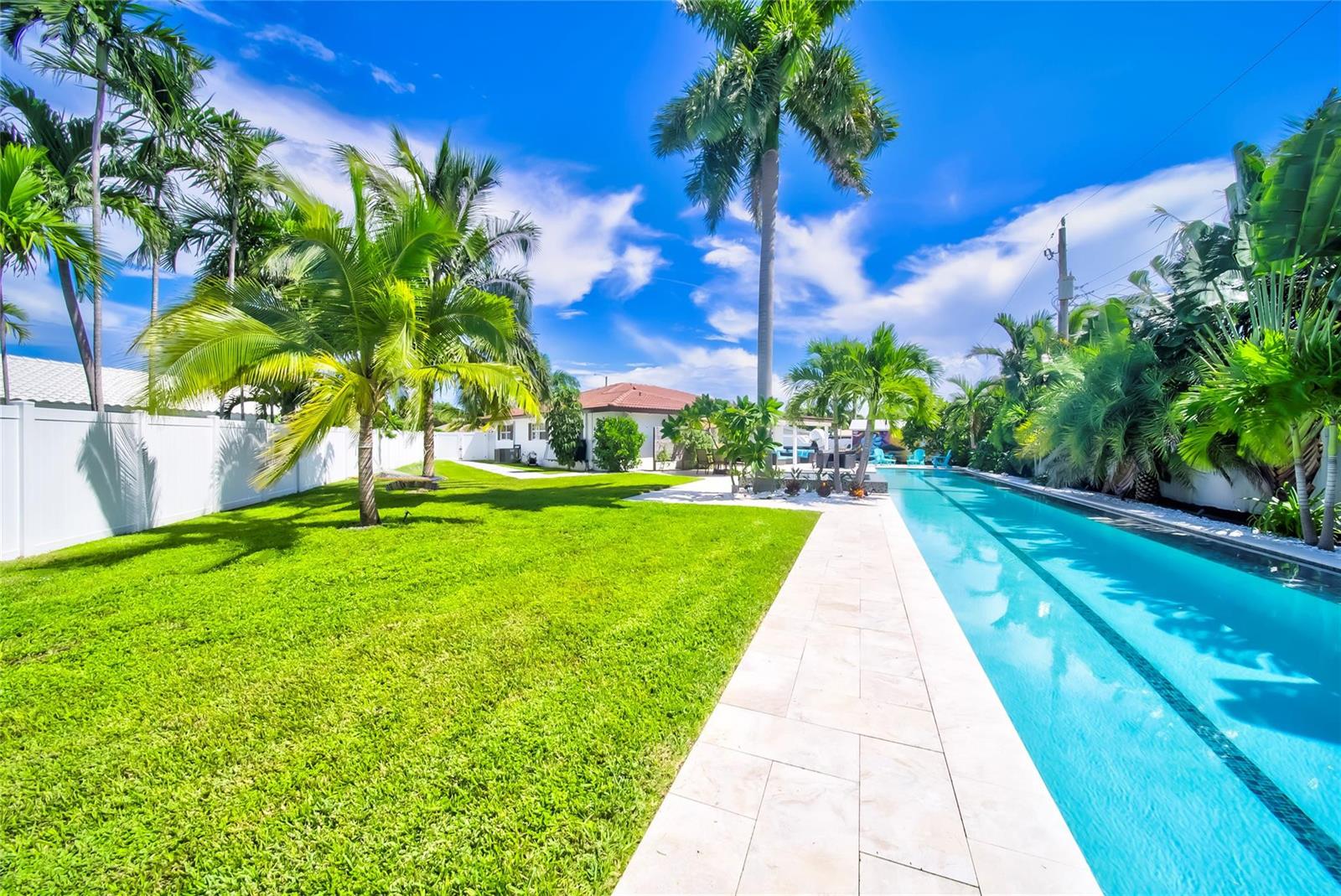 A long lap pool sits beside a grassy lawn and a white fence in a backyard — 250 NE 27th Court, Boca Raton FL 33431, BOCA RATON, FL