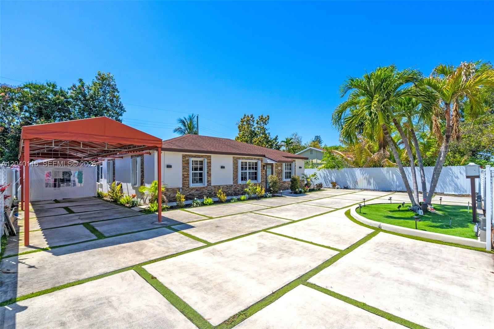A single-story house with a stone facade, a red carport, and a large concrete driveway — 302 NW 100th St, Miami FL 33150, MIAMI, FL