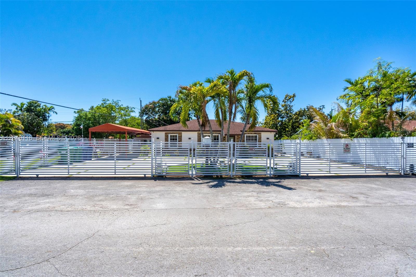 A single-story house with a white fence and palm trees sits behind a paved lot — 302 NW 100th St, Miami FL 33150, MIAMI, FL