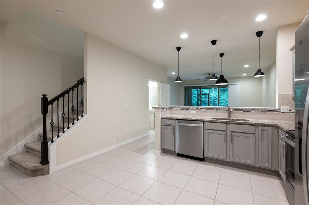 A kitchen with gray cabinets, granite countertops, and a staircase leading to an upper level — 1280 PAVIA DRIVE, APOPKA, FL