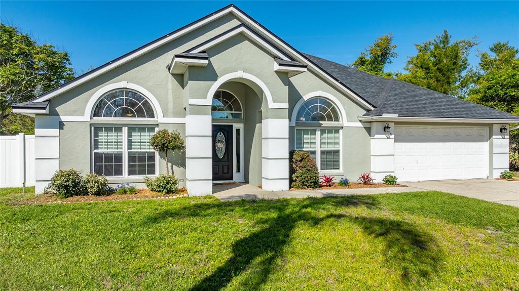 A single-story house with a light green stucco exterior, white trim, and a two-car garage — 5 FARR PLACE, PALM COAST, FL