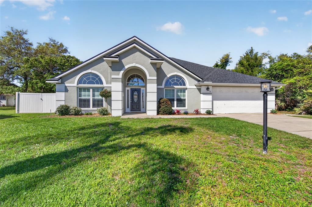 A single-story house with a gray stucco exterior, arched windows, and an attached two-car garage — 5 FARR PLACE, PALM COAST, FL