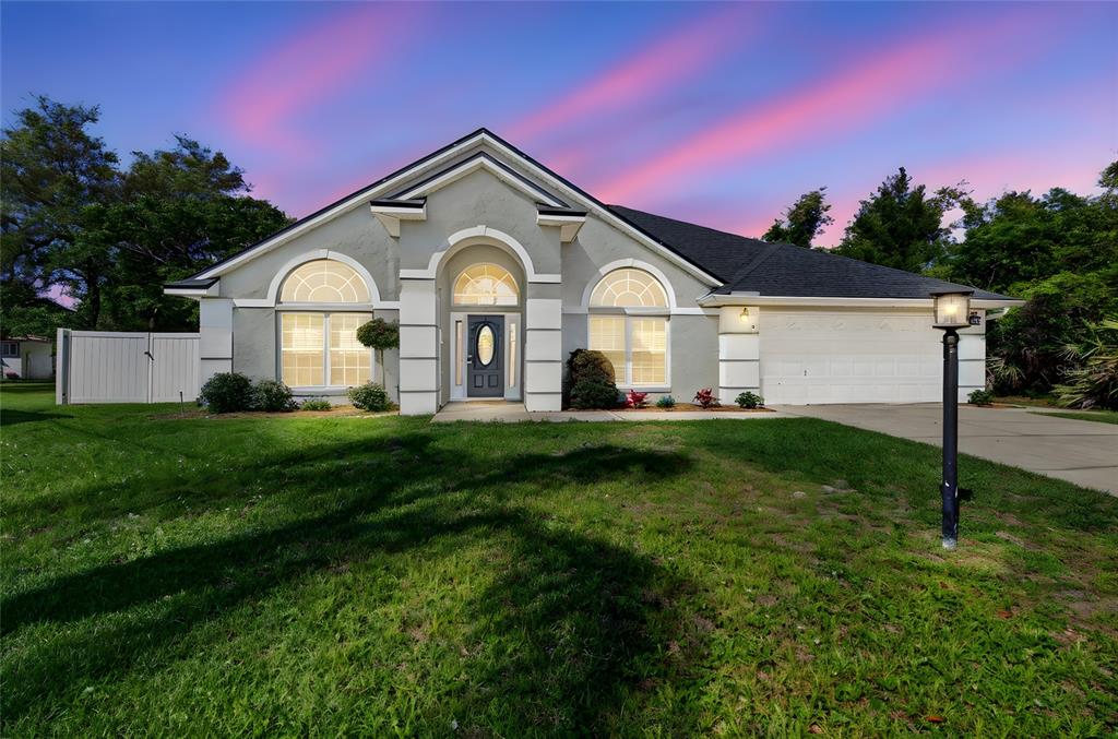 A single-story house with a gray exterior, arched windows, and a two-car garage at sunset — 5 FARR PLACE, PALM COAST, FL