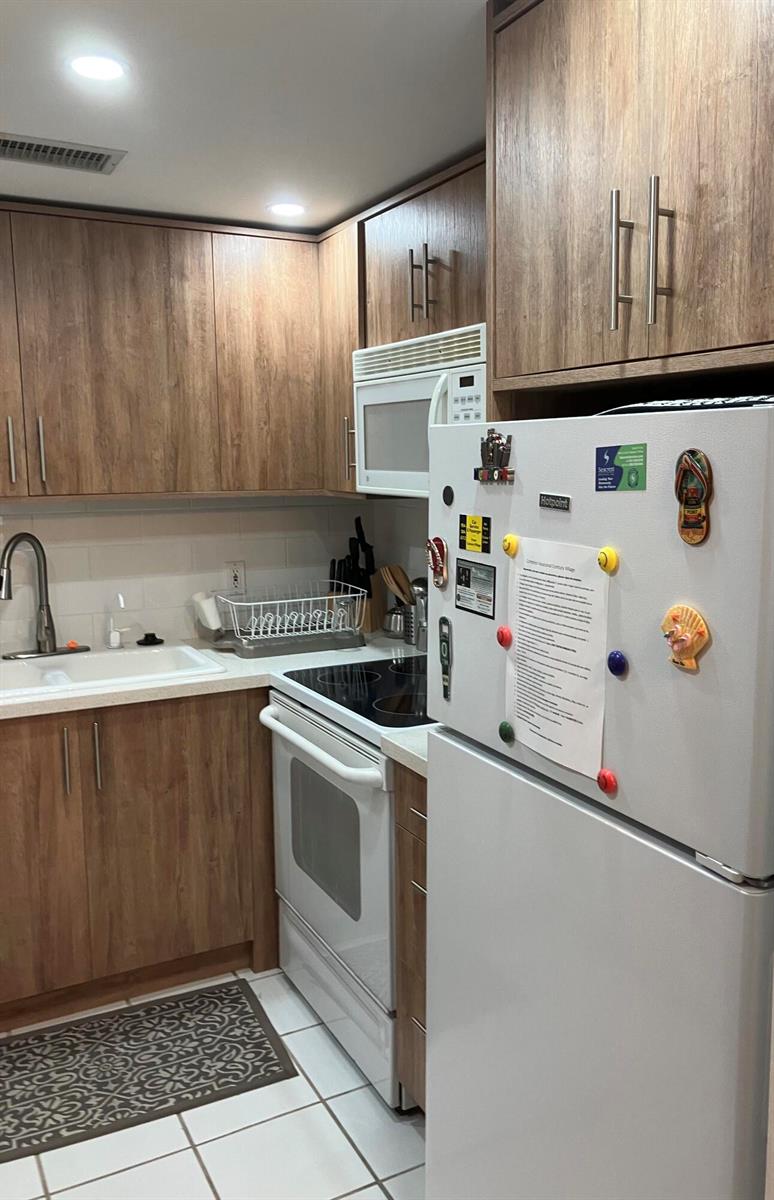 A kitchen featuring wood-grain cabinets, white appliances, a white tile backsplash, and a white refrigerator — 283 Durham H # 283, Deerfield Beach FL 33442, DEERFIELD BEACH, FL