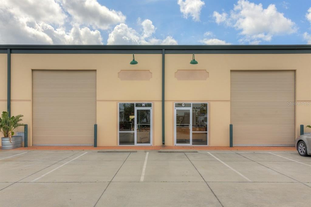 The exterior of a commercial building features two roll-up doors and two glass entry doors — 1220 BISCAYNE BOULEVARD, DELAND, FL