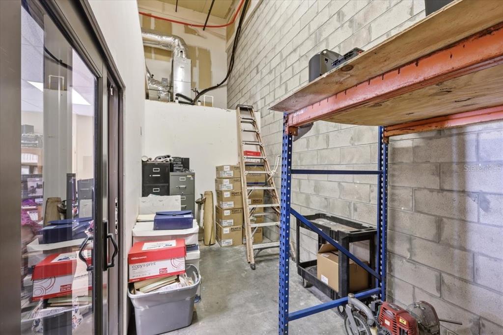 A storage area with a ladder, stacked boxes, metal shelving, and a concrete block wall — 1220 BISCAYNE BOULEVARD, DELAND, FL
