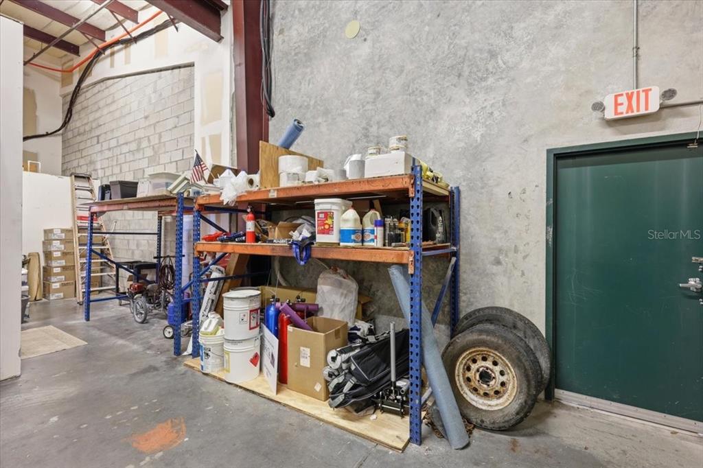 A warehouse interior features metal storage shelving units filled with supplies, tools, and spare tires — 1220 BISCAYNE BOULEVARD, DELAND, FL
