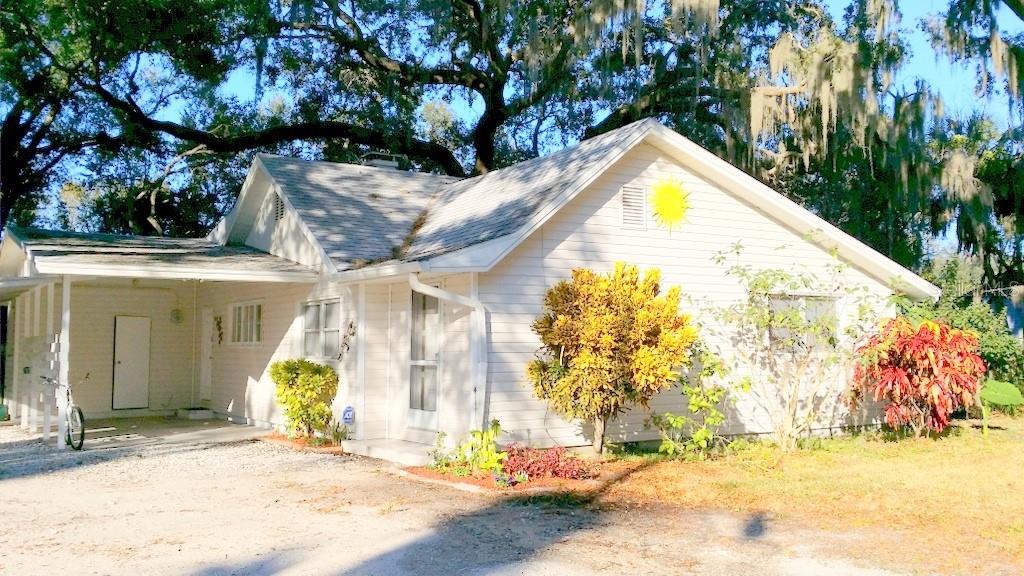 A white, single-story house with a carport and a yellow sun decoration on the siding — 1157 41ST STREET, SARASOTA, FL