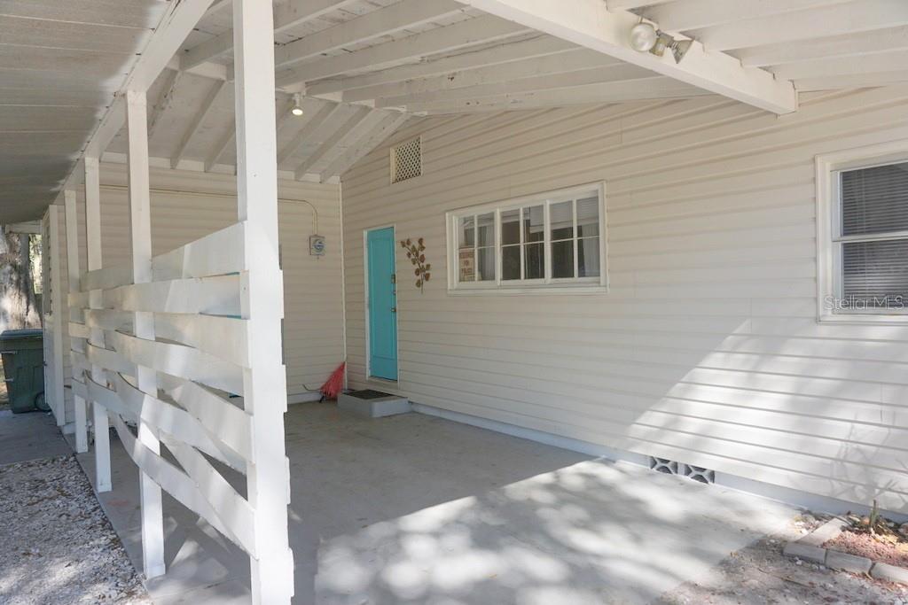 A covered concrete patio features white horizontal siding, a bright blue door, and a lattice wall — 1157 41ST STREET, SARASOTA, FL