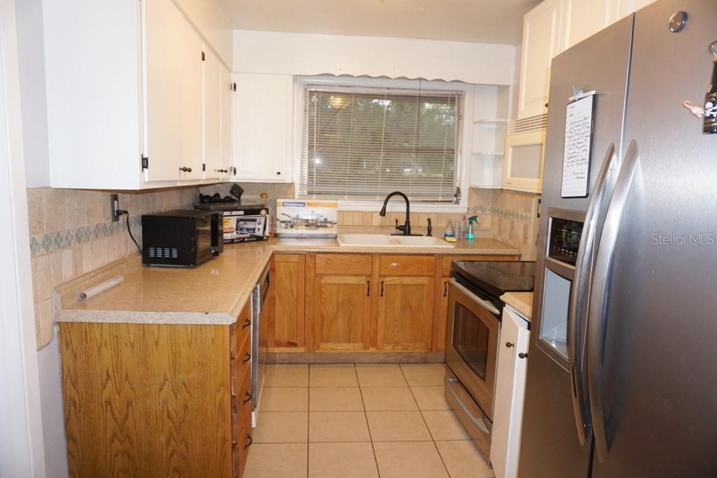A kitchen with white upper cabinets, wood lower cabinets, stainless steel appliances, and tile flooring — 1157 41ST STREET, SARASOTA, FL