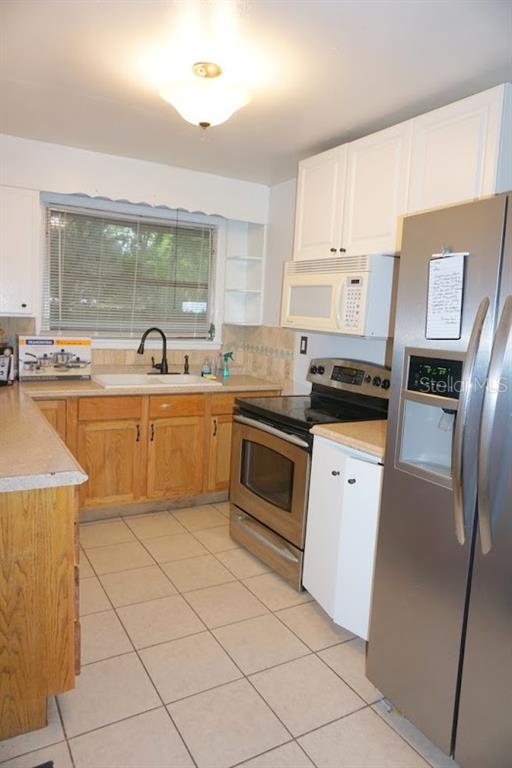 A kitchen with light wood cabinets, white upper cabinets, stainless steel appliances, and tiled floors — 1157 41ST STREET, SARASOTA, FL