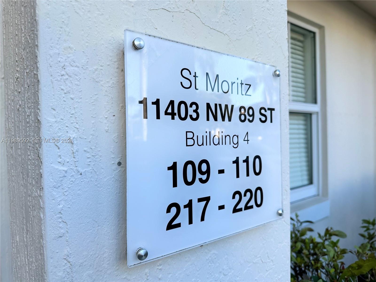 A white sign on a textured wall displays building and unit information for a complex — 11403 NW 89th St # 219, Doral FL 33178, DORAL, FL