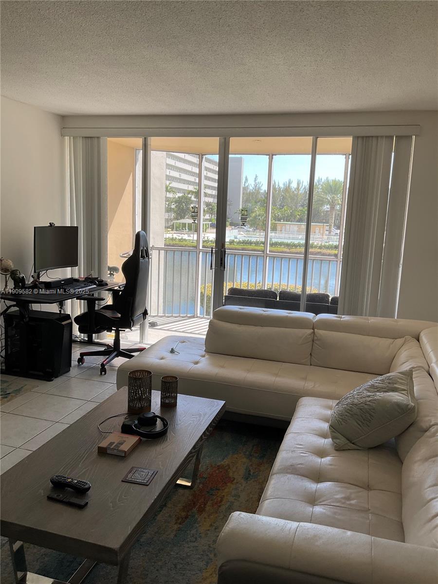 A living room features a white sectional sofa, a coffee table, and a desk area — 1770 NE 191st St # 1, Miami FL 33179, MIAMI, FL